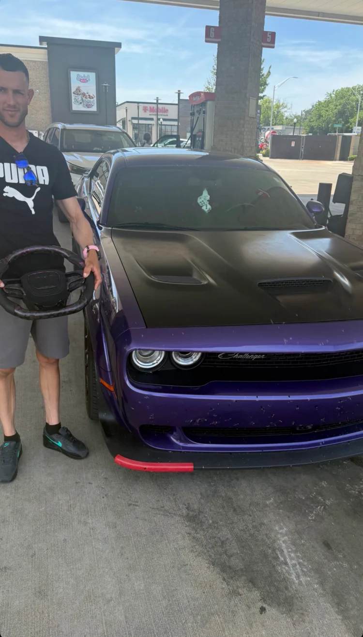 Customer with a custom wheel next to a purple Dodge Challenger